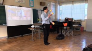3つのボールのジャグリングの解説をする大道芸人丸ちぇろ。滋賀県富士宮市黒田小学校にてキャリア教育出前授業の講師をさせていただきました。